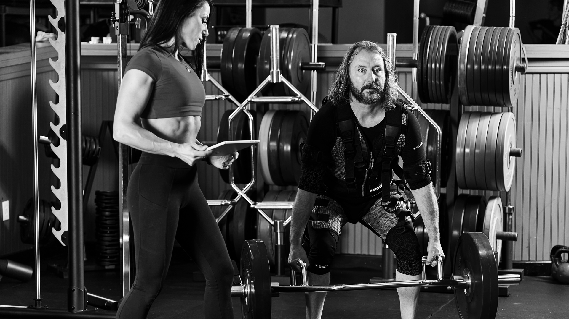 A black-and-white picture of a man with weights squatting